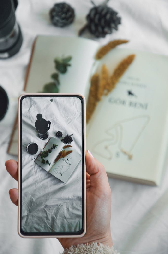 A person holding a smartphone with a photo of a book and a candle